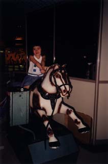Petite fille à califourchon sur un cheval de manège.