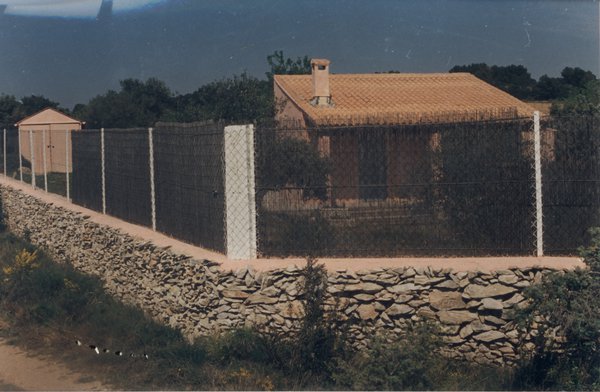 Mur de clôture avec grillage et maison provençale en arrière-plan