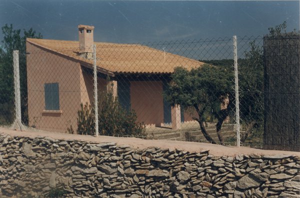 Mur de clôture avec grillage et maison provençale en arrière-plan.