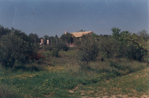 Maison provençale et grillage dans un paysage sous un ciel bleu.