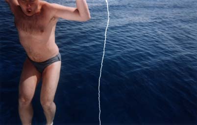 Homme debout en maillot, la mer en arrière-plan. Image déchirée, reconstituée.