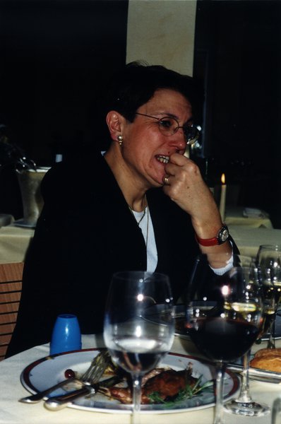 Femme à lunettes assise à une table devant les restes d’un repas.