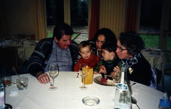 Homme, femme et enfants soufflent des bougies devant un goûter d’anniversaire.
