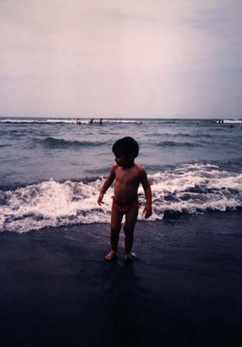 Enfant au bord de la mer, les pieds dans l’eau.