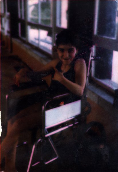 Enfant souriant dans un fauteuil roulant.