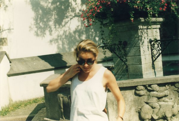 Femme blonde à lunettes noires de face.
