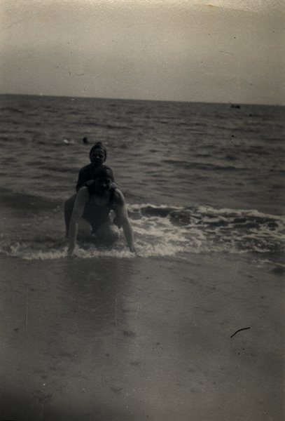 Deux personnes dans les vagues au bord de la mer, bonnets de bain. Noir et blanc.ᴬᴵ