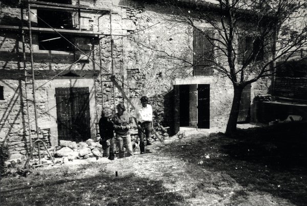 Trois hommes devant une maison en pierre en travaux. Noir et blanc.ᴬᴵ