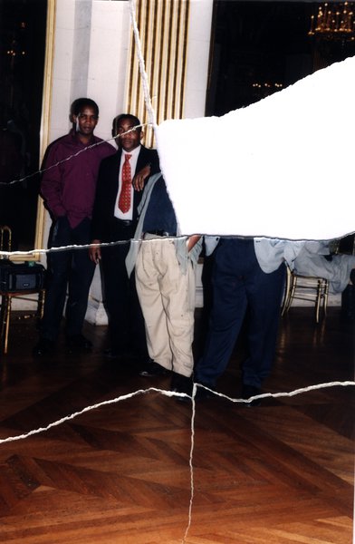 Trois hommes en tenue de soirée dans une salle avec lustre. Image avec déchirure, reconstituée.ᴬᴵ