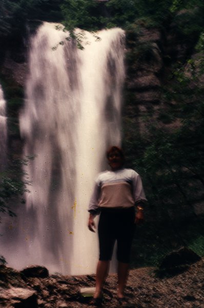 Femme debout devant une grande cascade.ᴬᴵ