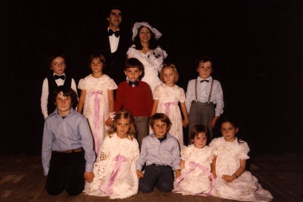 Photo de groupe d'un couple de mariés entouré d'enfants en tenue assortie.ᴬᴵ