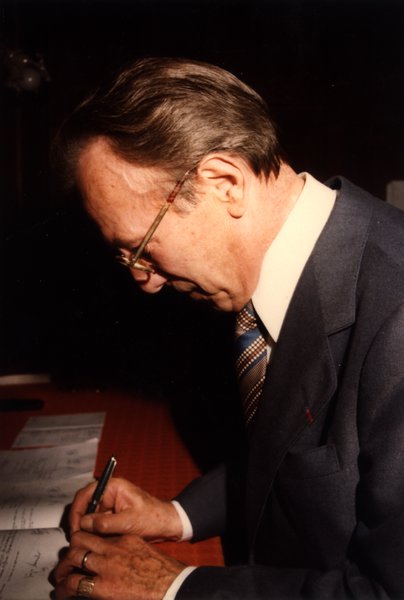 Homme en costume signant un document.ᴬᴵ