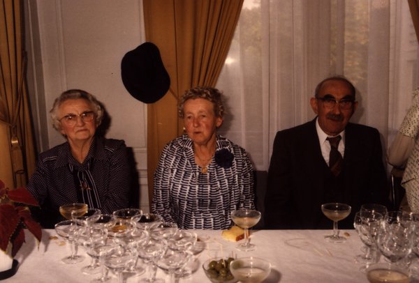 Deux femmes âgées et un homme âgé assis à une table de repas.ᴬᴵ