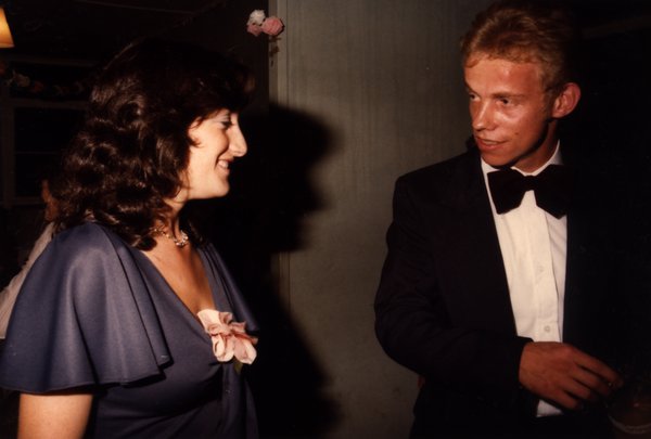 Femme aux cheveux bruns bouclés discutant avec un jeune homme blond en smoking.ᴬᴵ