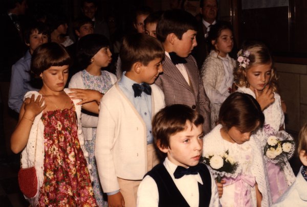 Groupe d'enfants habillés en tenue de cérémonie à l'intérieur d'une église.ᴬᴵ