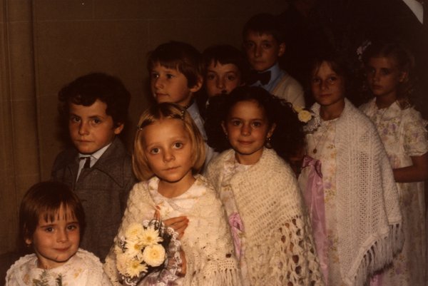 Groupe d'enfants posant, certains avec châle en crochet et bouquet.ᴬᴵ