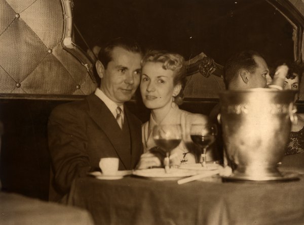 Couple attablé dans un restaurant avec verres de vin et seau à glace. Noir et blanc.ᴬᴵ