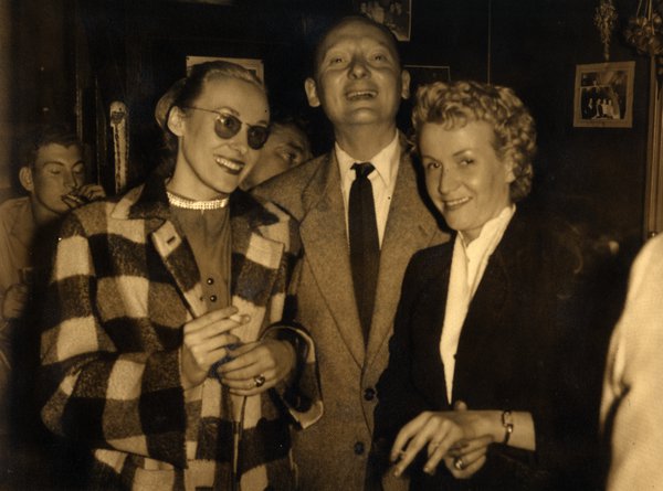 Trois personnes souriant lors d'une soirée. Noir et blanc.ᴬᴵ