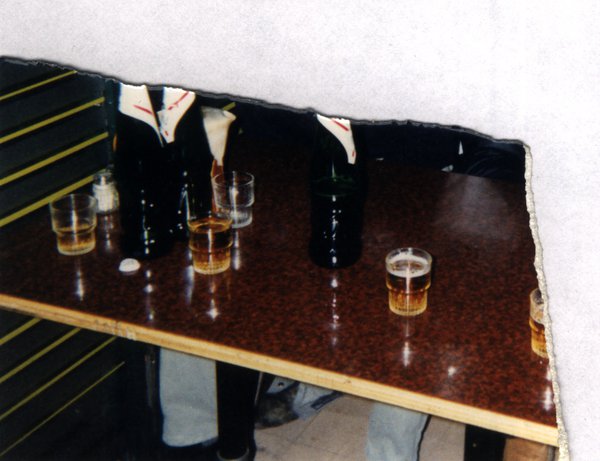 Table avec bouteilles et verres d'alcool. Fragment déchiré.ᴬᴵ
