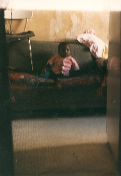 Enfant assis sur un canapé où est posée une chaise.
