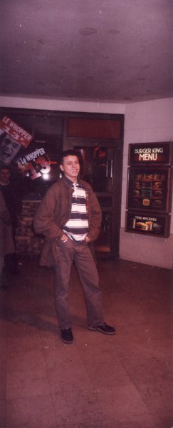 Jeune homme debout souriant à l’entrée d’un restaurant.