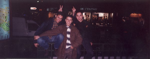 Trois Jeunes homme souriants accolés prennent la pose dans un bar.