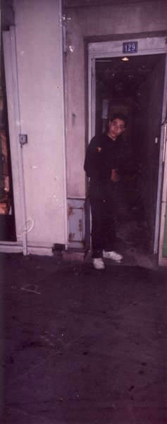 Jeunes hommes de type magrébin debout dans l’embrasure d’une porte de nuit.