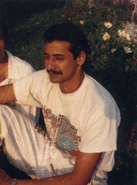 Homme moustachu assis en tailleur.
