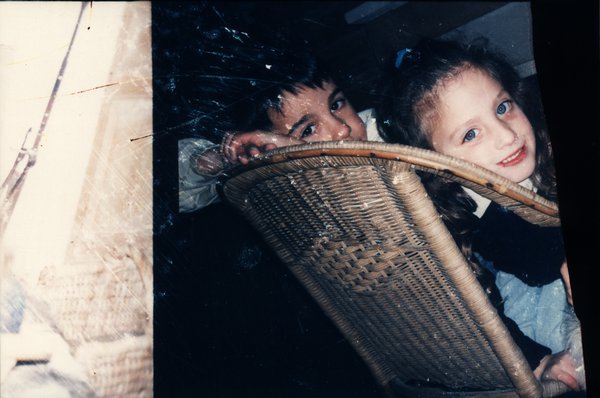 Deux enfants regardant par-dessus le dossier d'une chaise en osier.ᴬᴵ