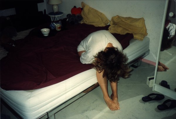 Femme assise au bord d'un lit, tête penchée, cheveux dénoués.ᴬᴵ