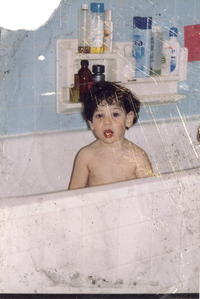 Un petit enfant brun dans son bain. Image abîmée.