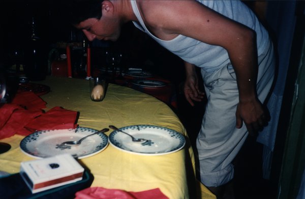 Homme penché au-dessus d'une table avec assiettes et bouchon de liège dressé, jeu de soirée.ᴬᴵ