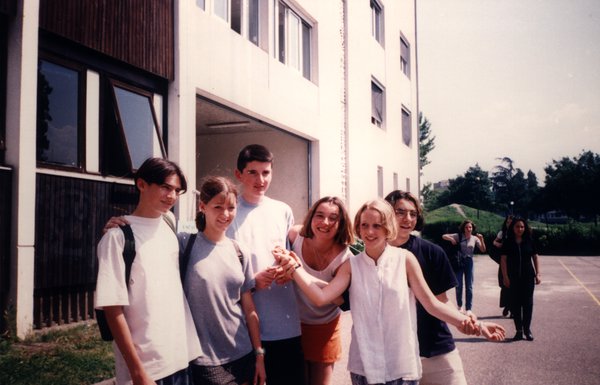 Groupe d'adolescents posant devant un bâtiment scolaire.ᴬᴵ