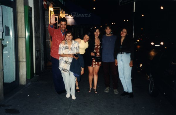 Groupe posant dans une rue de nuit près d'une boutique de fleurs.ᴬᴵ