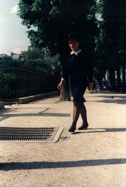 Femme en tenue marine marchant sur une allée de gravier dans un parc.ᴬᴵ
