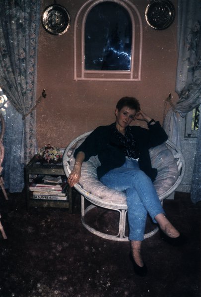 Femme assise dans un fauteuil en osier avec des livres à côté.ᴬᴵ