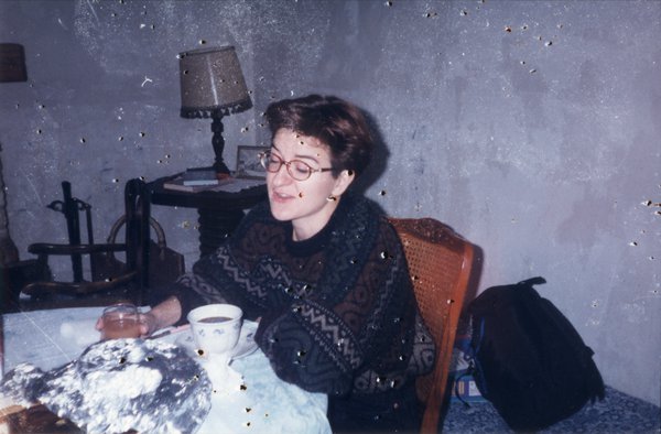 Femme brune à lunettes en pull jacquard attablée.