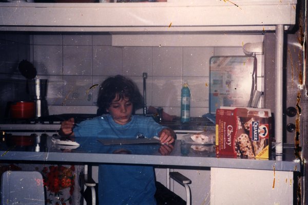 Enfant prenant son petit-déjeuner dans une cuisine.ᴬᴵ