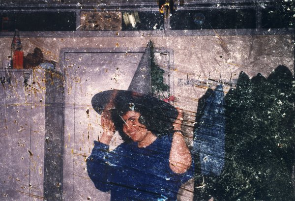 Femme brune souriante en pull bleu avec un chapeau conique sur la tête. Image avec rayures.
