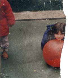 Petite fille brune avec un ballon orange. Fragment.