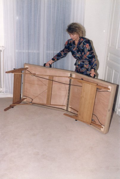 Femme blonde repliant un lit pliant dans un appartement.