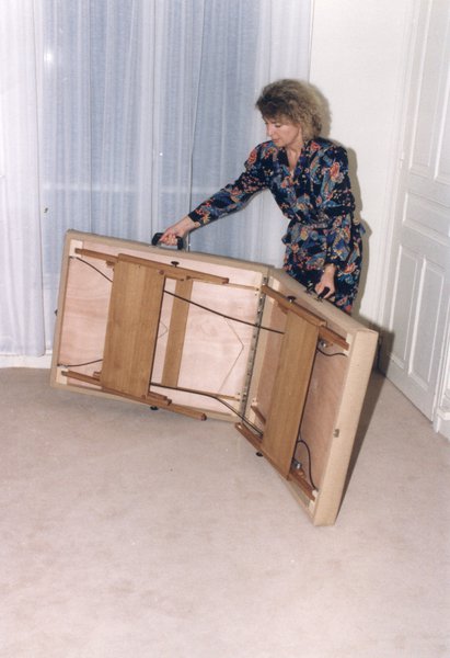 Femme blonde repliant un lit pliant dans un appartement.