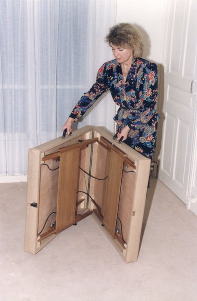 Femme blonde repliant un lit pliant dans un appartement.