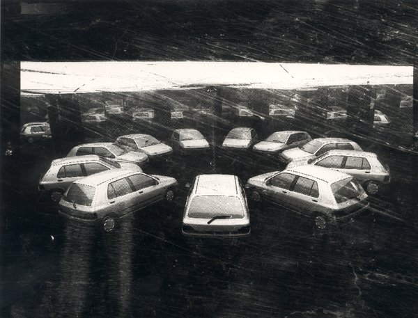 Voitures disposées en rosace devant un miroir. Image avec rayures. Noir et blanc.