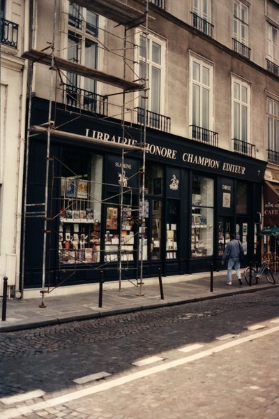 Devanture de l’éditeur et libraire Honoré Champion  avec des échafaudages dans une rue parisienne.