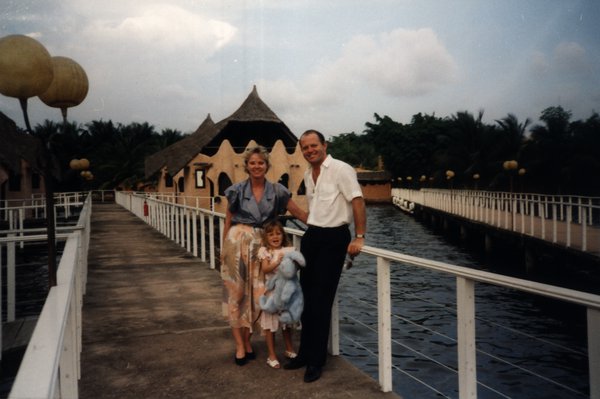 Famille sur une passerelle en bois au-dessus de l'eau dans un complexe tropical.ᴬᴵ