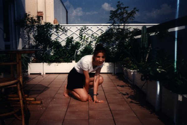 Femme agenouillée sur une terrasse carrelée avec des plantes.ᴬᴵ