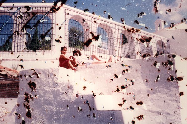 Deux enfants assis sur un muret avec balustrade en fer forgé. Image très abîmée par des taches.ᴬᴵ