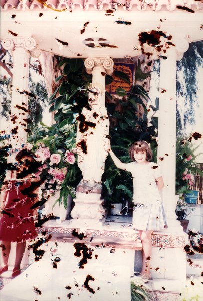 Fillette près d'un kiosque orné de fleurs. Image avec de nombreuses taches.ᴬᴵ