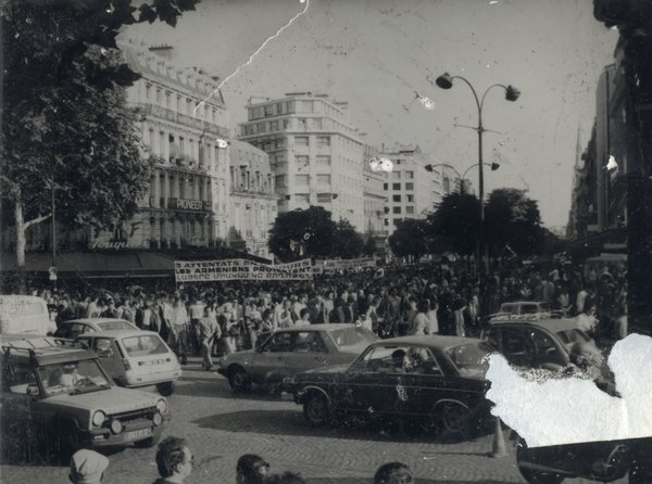 Foule avec manifestants dans la rue et voitures. Noir et blanc.